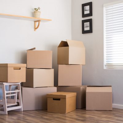 Moving house and boxes Stack of cardboard boxes in an empty room. Pile of carton boxes on the floor in an empty apartment. Stack of moving boxes in new house.